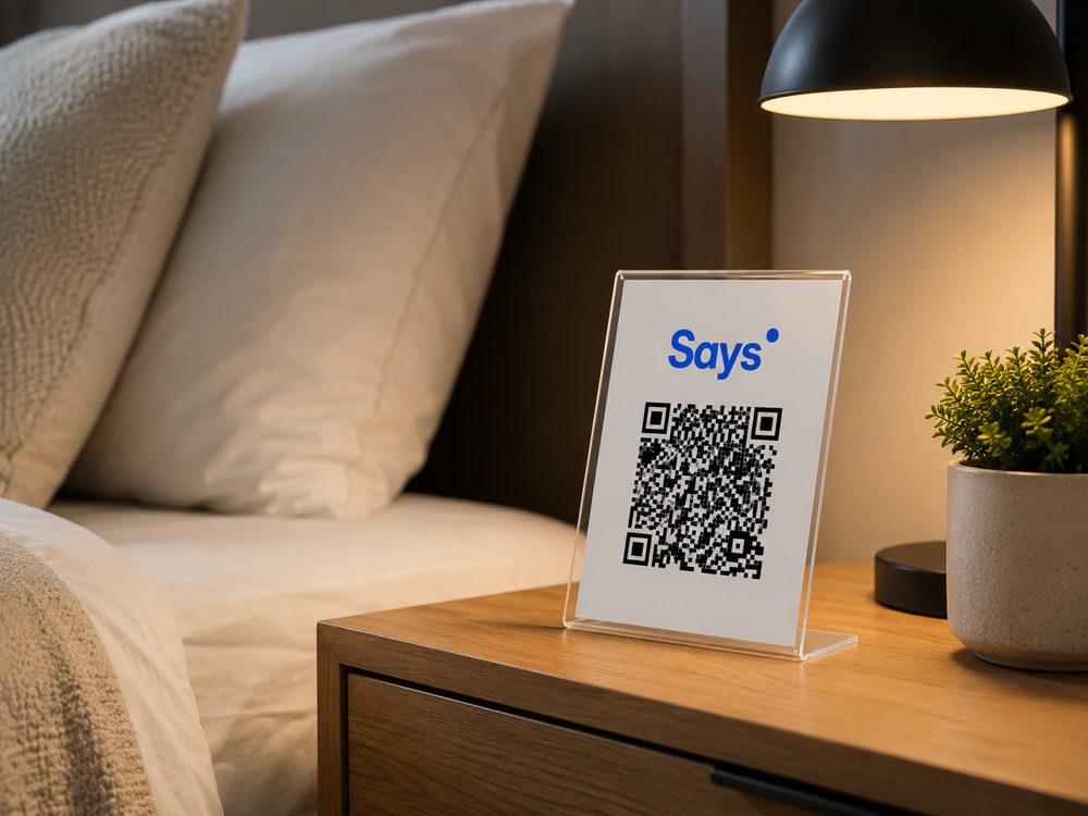 QR code do Says Host em suporte no criado-mudo do quarto